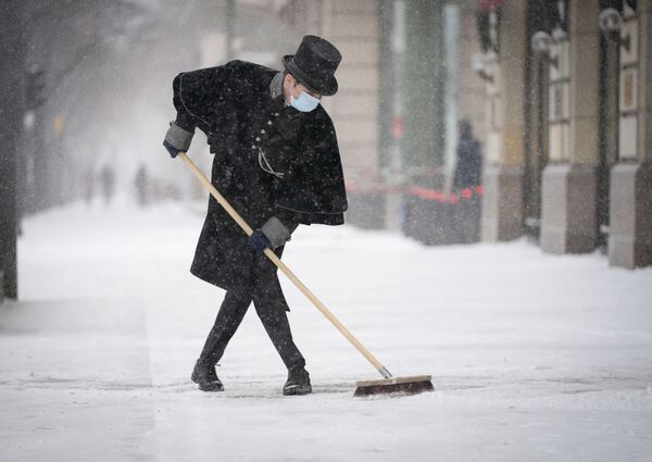 Сотрудник отеля Adlon чистит тротуар от снега на Парижской площади в Берлине - Sputnik Грузия