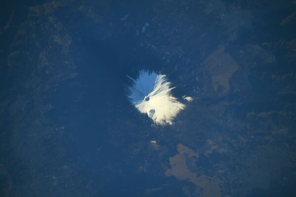 Заснеженная гора Фудзияма в Японии, снятая японским космонавтом Соити Ногути. На фото изображен действующий стратовулкан на острове Хонсю - Sputnik Грузия