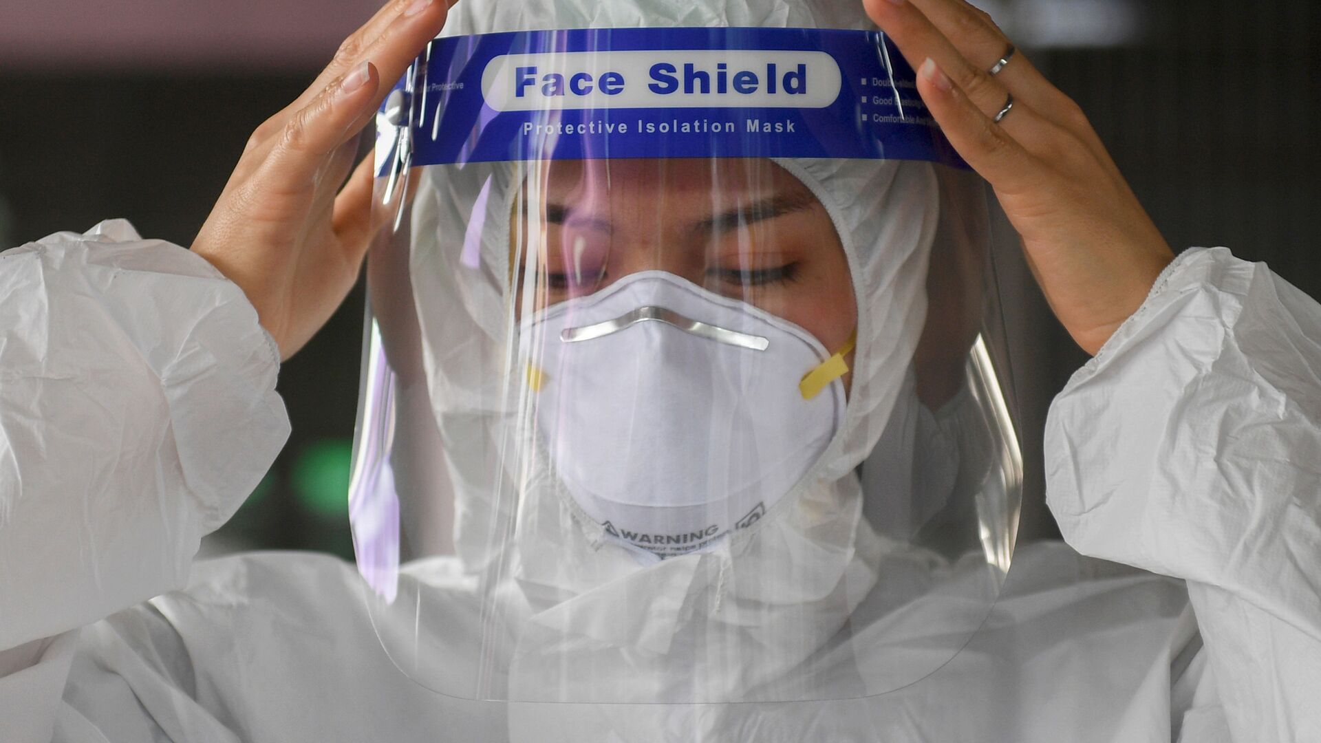 Пандемия коронавируса COVID - женщина надевает лицевую маску и защитный костюм - Sputnik Грузия, 1920, 17.01.2022