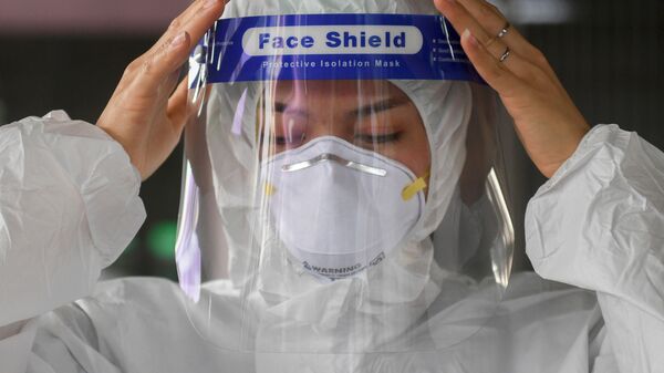 Пандемия коронавируса COVID - женщина надевает лицевую маску и защитный костюм - Sputnik Грузия