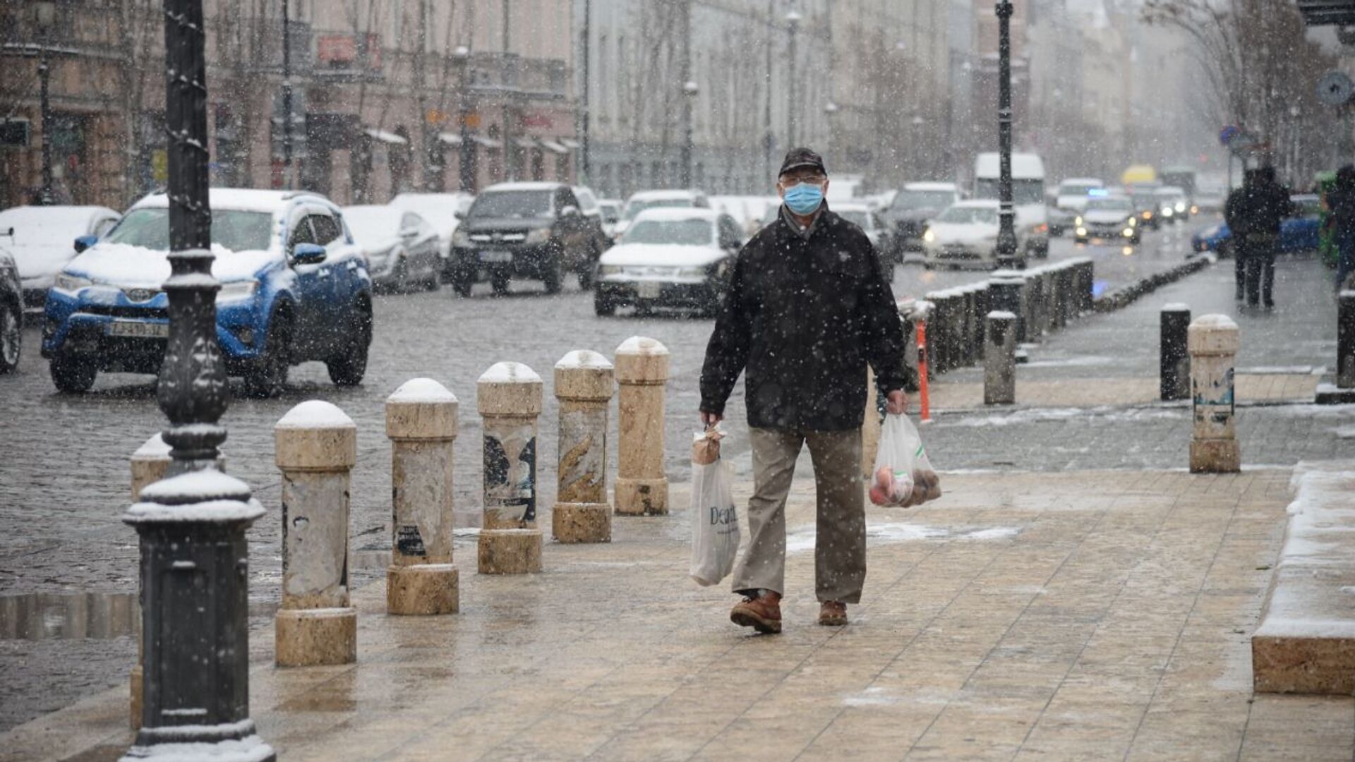 Эпидемия коронавируса - мужчина идет по улице в маске в снег - Sputnik Грузия, 1920, 22.03.2022