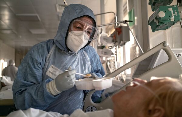 Медсестра кормит пациента в отделении реанимации и интенсивной терапии в больнице в Москве - Sputnik Грузия