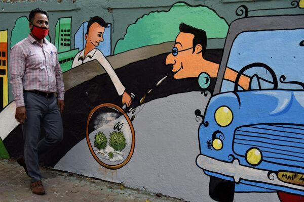 Пешеход идет мимо стены с граффити на тему коронавируса в Индии - Sputnik Грузия