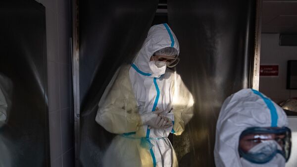 Медик, одетый в СИЗ, проходит через дезинфекционную камеру Московской городской клинической больницы № 15 (больница имени Филатова) - Sputnik Грузия