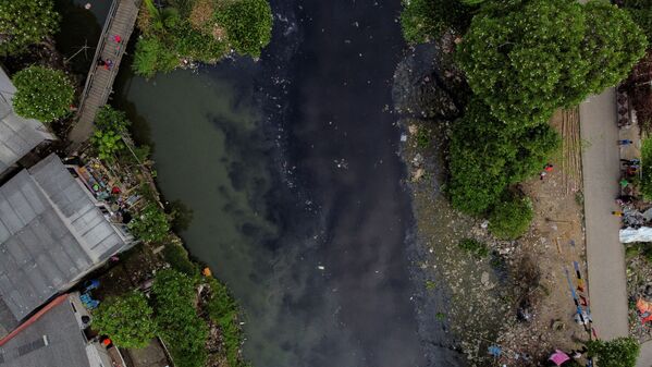 По оценкам Всемирной организации здравоохранения (ВОЗ) 80 % заболеваний в мире вызваны неподобающим качеством и антисанитарным состоянием воды. На фото: люди ловят рыбу с деревянного моста на реке Писанг-Бату, протекающей через густонаселенный район загрязненной бытовыми отходами на окраине Джакарты - Sputnik Грузия