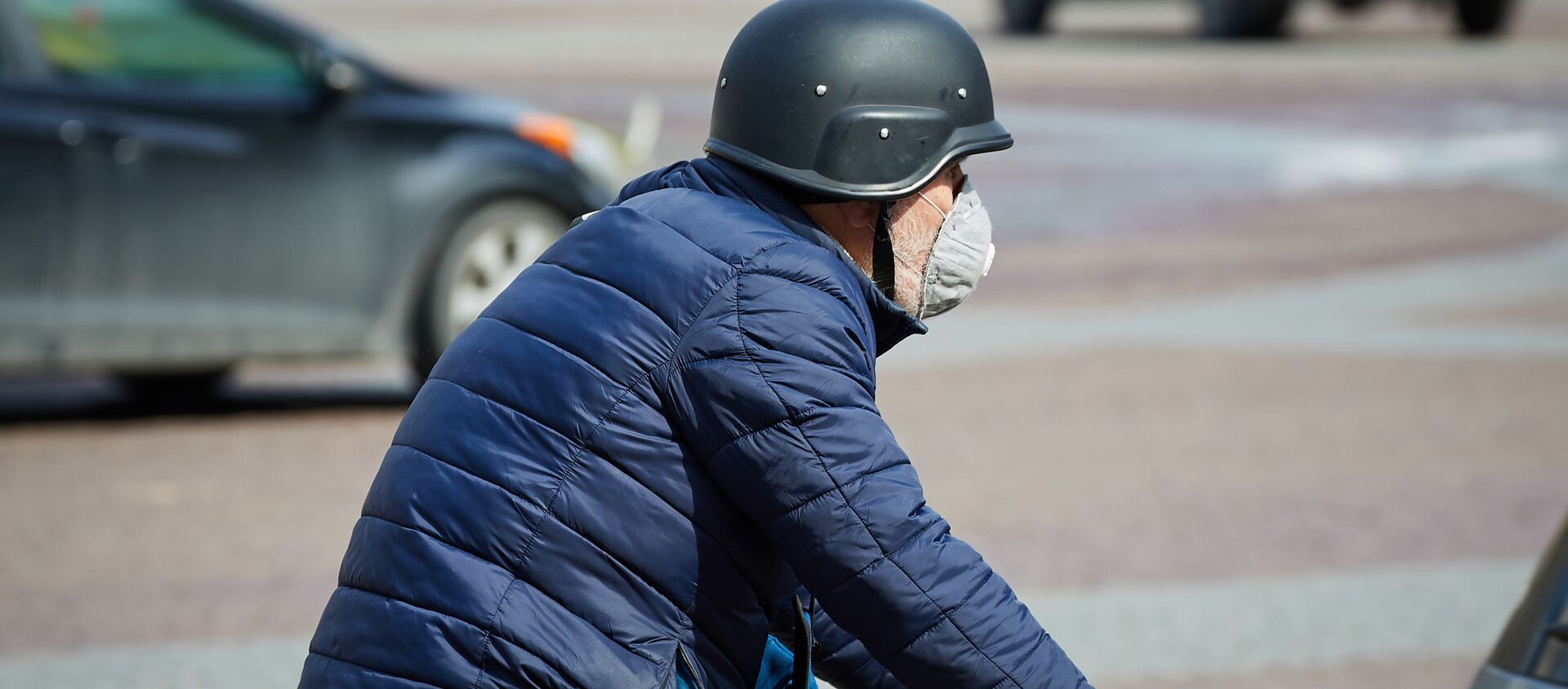 Эпидемия коронавируса - пожилой мужчина в каске и защитном респираторе едет на велосипеде по площади Свободы - Sputnik Грузия, 1920, 22.03.2021