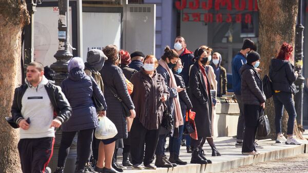 Эпидемия коронавируса - прохожие на автобусной остановке в масках - Sputnik Грузия