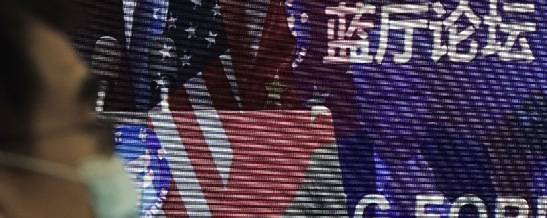 Мужчина в маске, помогающей сдержать распространение коронавируса, сидит возле экрана, демонстрирующего, как делегаты присутствуют на форуме Лантинга, посвященном приезду Китая и США. отношения вернулись в правильное русло, которое под председательством министра иностранных дел Китая Ван И в офисе Министерства иностранных дел в Пекине в понедельник, 22 февраля 2021 года. В понедельник Ван призвал США снять ограничения на торговлю и контакты между людьми при прекращении того, что Пекин считает необоснованным вмешательством в районы Тайваня, Гонконга, Синьцзяна и Тибета - Sputnik Грузия, 1920, 16.04.2021
