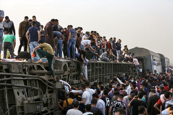 Люди поднимаются на перевернутый вагон после аварии поезда в Египте - Sputnik Грузия
