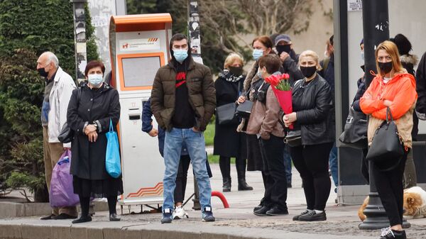 Эпидемия коронавируса - прохожие на автобусной остановке в масках - Sputnik Грузия