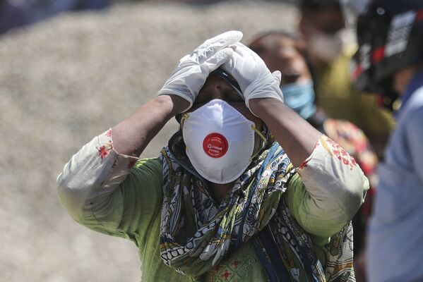 Сегодня в Индии не знают, как остановить активное распространение коронавируса. На фото - один из жителей скорбит по погибшему родственнику во время процедуры кремации в городе Джамму - Sputnik Грузия