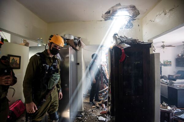 Солдаты работают у здания, поврежденного ракетой, запущенной из сектора Газа в Ашдоде на юге Израиля - Sputnik Грузия