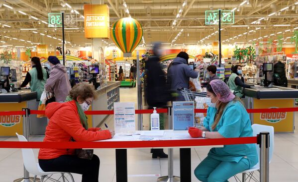 Женщина заполняет документы перед вакцинацией от COVID-19 российской вакциной Спутник V (Гам-КОВИД-Вак) в гипермаркете Глобус в Москве - Sputnik Грузия
