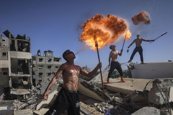 Члены палестинской команды Bar Woolf из Газы выступают с файер-шоу на руинах здания, разрушенного в результате израильских авиаударов - Sputnik Грузия