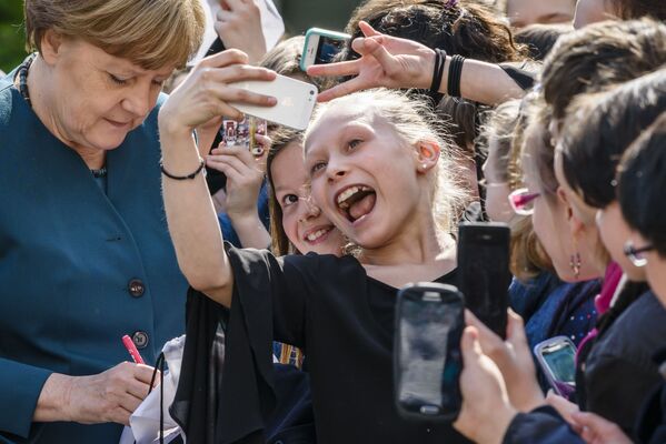 Канцлер Германии Ангела Меркель во время раздачи автографов школьникам в Берлине - Sputnik Грузия