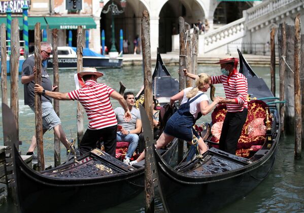 Гондольеры помогают туристам сесть в гондолы в Венеции - Sputnik Грузия