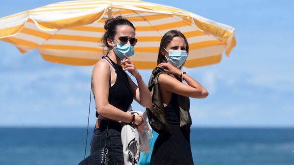 Люди в защитных масках гуляют по пляжу во Франции - Sputnik Грузия