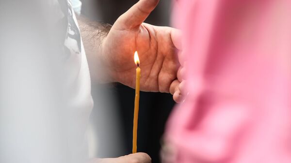 Верующие держат в руках горящие свечи во время молитвы - Sputnik Грузия