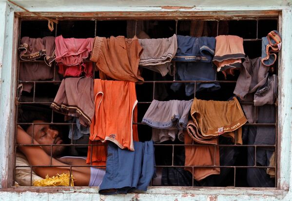 Обитатель трущоб спит у окна, завешанного бельем сушиться, в лачуге в Дхарави, Мумбаи - Sputnik Грузия