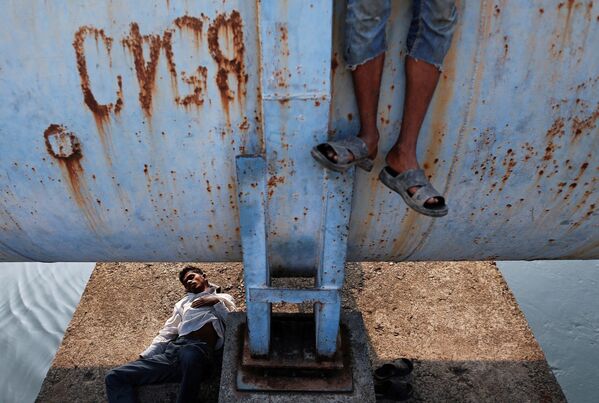 Мужчина спит под водопроводом, в то время как другой стоит на нем в Мумбаи - Sputnik Грузия