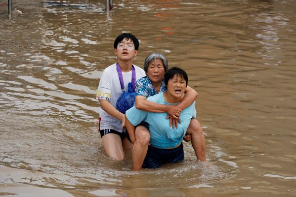 Мать и сын спасают пожилую бабушку, идя по пояс в воде во время наводнения в Чжэнчжоу, провинция Хэнань - Sputnik Грузия