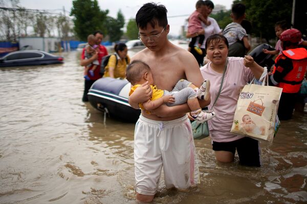 Супружеская пара с малышом пробирается по затопленной дороге в Чжэнчжоу, провинция Хэнань  - Sputnik Грузия