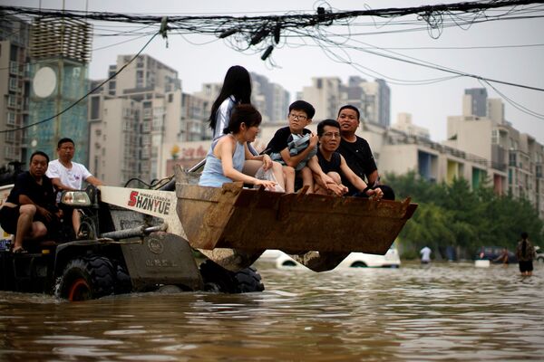 С помощью грузового фронтального погрузчика люди в его ковше выбираются из зоны бедствия в  Чжэнчжоу, провинция Хэнань  - Sputnik Грузия