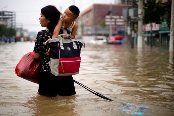 Женщина с ребенком и вещами ищет путь к спасению, выбираясь из Чжэнчжоу, провинция Хэнань, через затопленные улицы - Sputnik Грузия