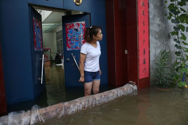 Девушка смотрит на затопленные улицы и здания в деревне Бейгуань, провинция Хэнань. Власти провинции эвакуировали из опасных районов более 860 тысяч человек - Sputnik Грузия