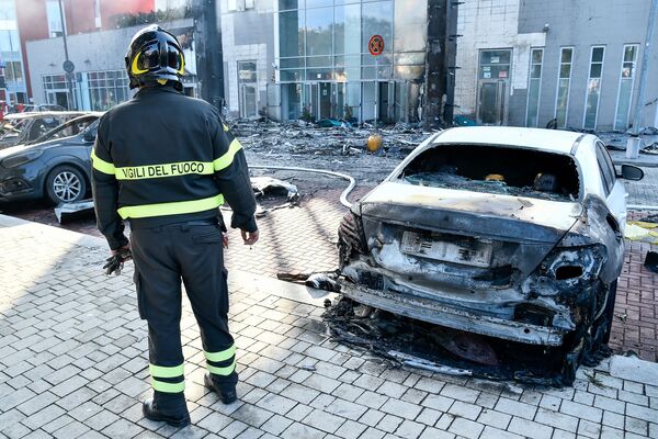 Пожарный стоит рядом со сгоревшей машиной после крупного пожара в многоквартирном доме в Милане - Sputnik Грузия