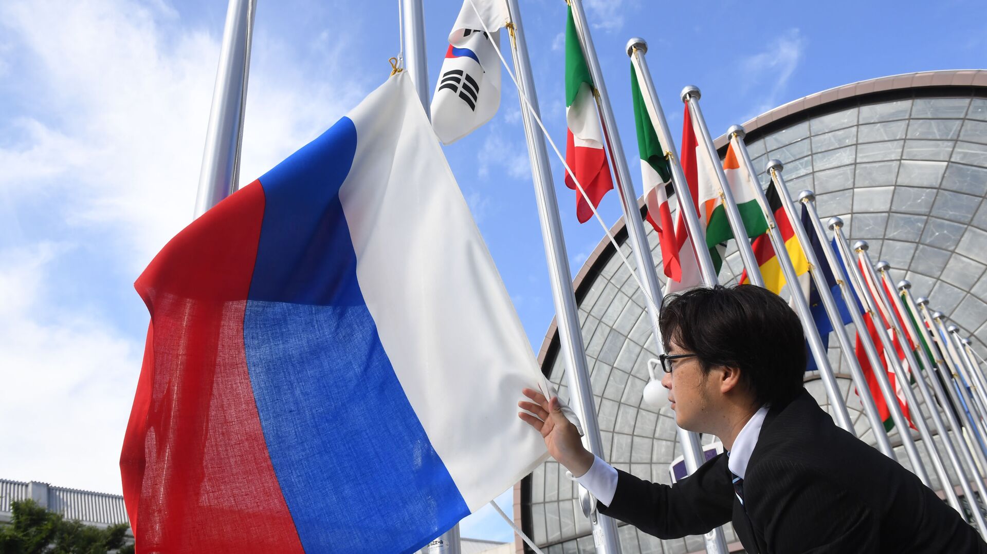 Вывешивание флага России у международного выставочного центра INTEX Osaka перед открытием саммита Группы двадцати в японской Осаке - Sputnik Грузия, 1920, 28.06.2022