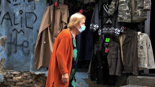 Эпидемия коронавируса - пожилая женщина идет мимо магазина одежды секонд-хенд - Sputnik Грузия