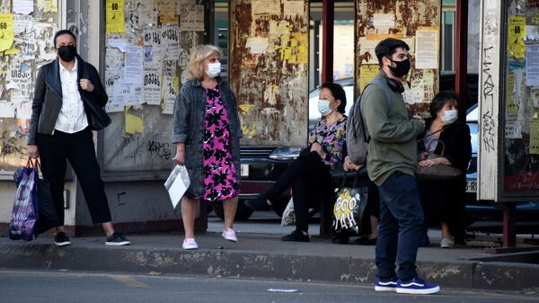 Эпидемия коронавируса - прохожие на улице в масках на автобусной остановке - Sputnik Грузия
