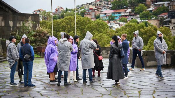 Туристы гуляют по Тбилиси в пасмурную погоду в дождевиках - Sputnik Грузия