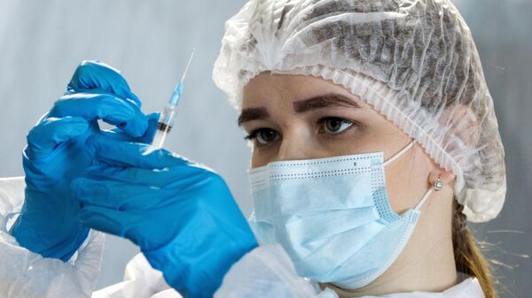 Медицинский сотрудник подготавливает шприц для вакцинации посетителей  - Sputnik Грузия
