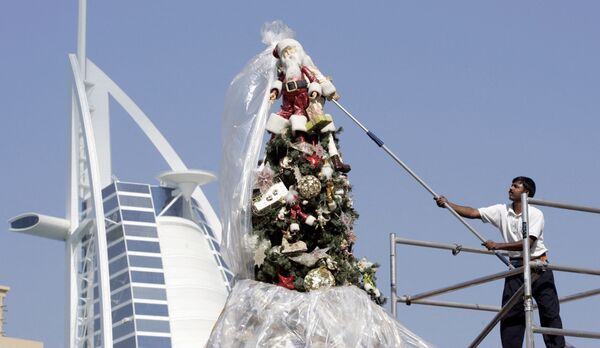 Рабочий в Дубае устанавливает рождественскую елку на пляже Джумейра в преддверии праздника - Sputnik Грузия