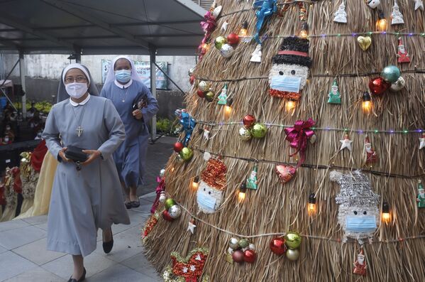 Монахини в масках проходят мимо рождественской елки с украшениями на тему коронавируса на Бали - Sputnik Грузия