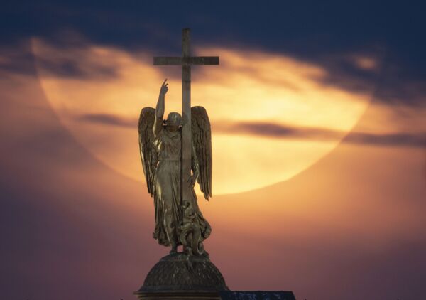 Полная луна поднимается к облакам над статуей ангела, установленной на вершине Александровской колонны на Дворцовой площади в Санкт-Петербурге - Sputnik Грузия