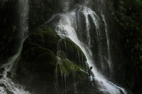 Паломник-вуду купается в водопаде, который, как считается, обладает очищающей силой, во время ежегодного праздника в Саут-д&#x27;О, Гаити.  - Sputnik Грузия
