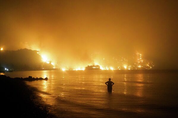 Мужчина наблюдает, как лесной пожар приближается к пляжу Кочили недалеко от деревни Лимни в Греции, примерно в 160 километрах к северу от Афин. Август 2021 года. - Sputnik Грузия