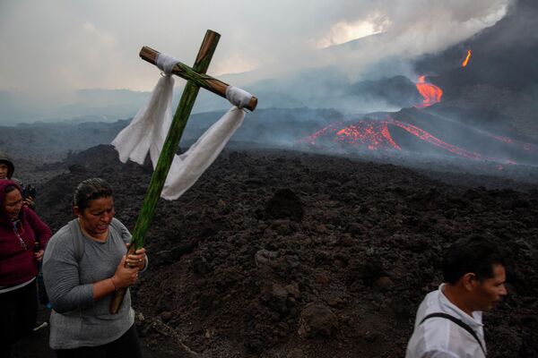 Женщина с крестом и другие паломники идут молиться, чтобы вулкан Пакая в Гватемале уменьшил свою активность. Вулкан, расположенный в 50 километрах к югу от столицы Гватемалы, стал извергаться с февраля 2021 года, а фото было сделано в мае.  - Sputnik Грузия