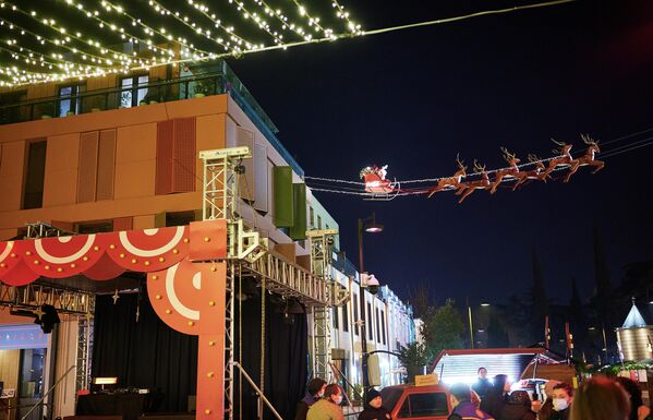 Неподалеку расположился летящий по воздуху Санта-Клаус в санях, которые везут новогодние олени.  - Sputnik Грузия