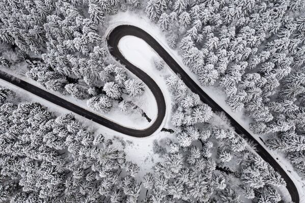 На этой фотографии, сделанной 9 декабря 2021 года, показан вид с высоты птичьего полета на дорогу в снежную погоду в Ксонрупт-Лонгемере, восточная Франция. - Sputnik Грузия