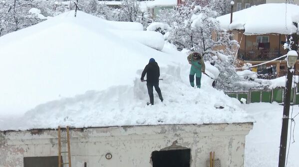 Когда прекращается снегопад, жители выходят, чтобы убрать огромные пласты снега с крыш домов. - Sputnik Грузия