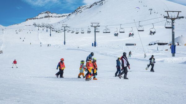 Зимний курорт Гудаури. Туристы идут кататься на лыжах на фоне подъемника - Sputnik Грузия