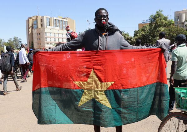 Мужчина держит в руках национальный флаг Буркина-Фасо - Sputnik Грузия