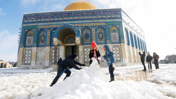 Дети строят снеговика перед мечетью Купол Скалы, расположенной в Старом городе Иерусалима - Sputnik Грузия