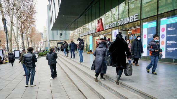 Эпидемия коронавируса - прохожие на улице в масках у торгового центра и станции метро Площадь Свободы - Sputnik Грузия