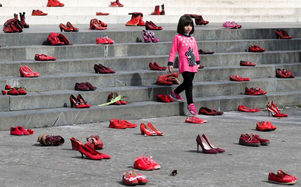 Девочка рядом с инсталляцией женских красных туфель, выставленных на лестнице как символ осуждения насилия в отношении женщин, в Тиране, Албания - Sputnik Грузия