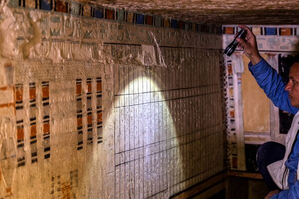 Археолог держит фонарь у стены, покрытой иероглифическими гравюрами, внутри гробницы Бети, одной из пяти древних гробниц фараонов - Sputnik Грузия